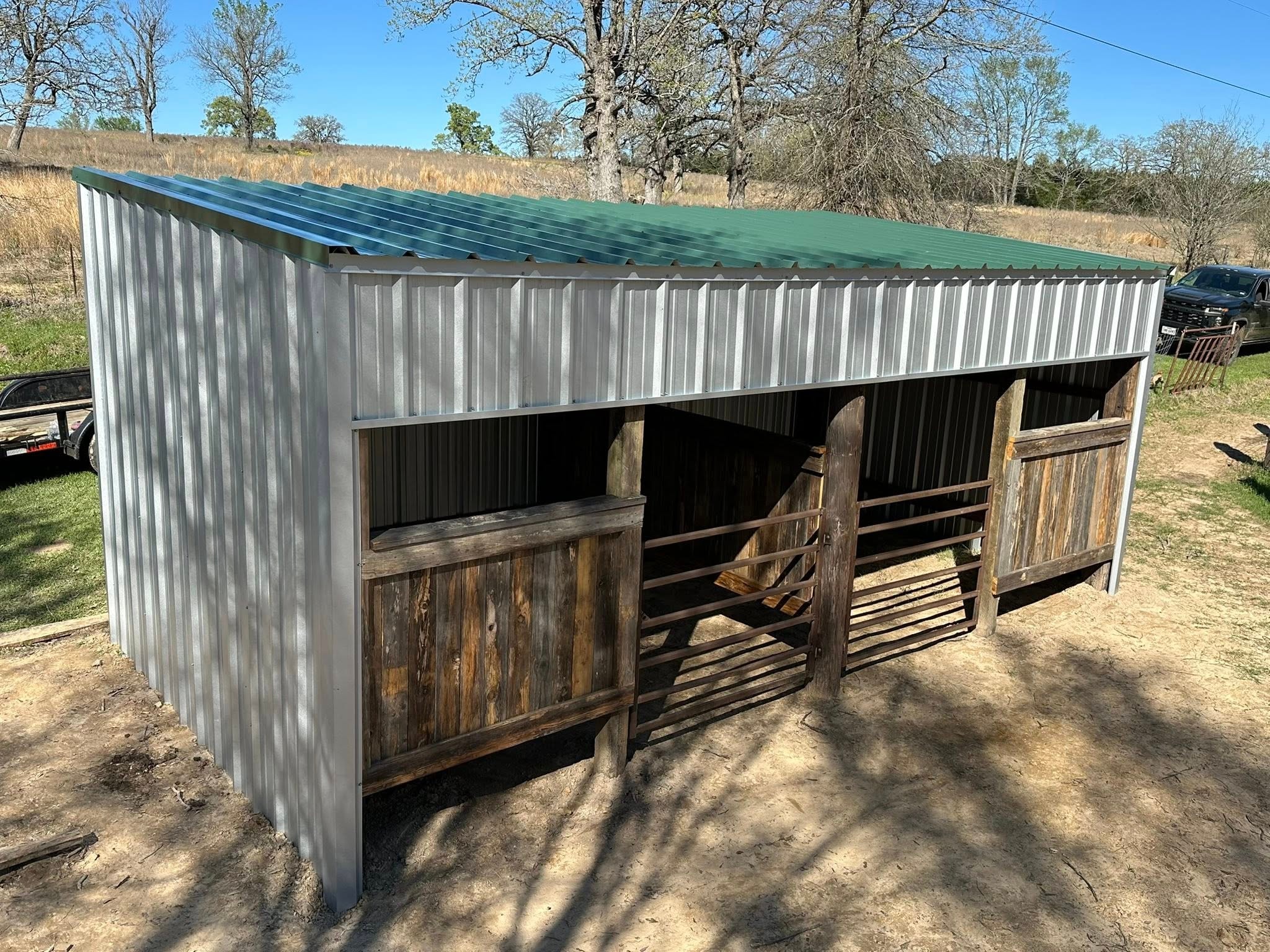 Metal horse shelter with green roof and stall gates