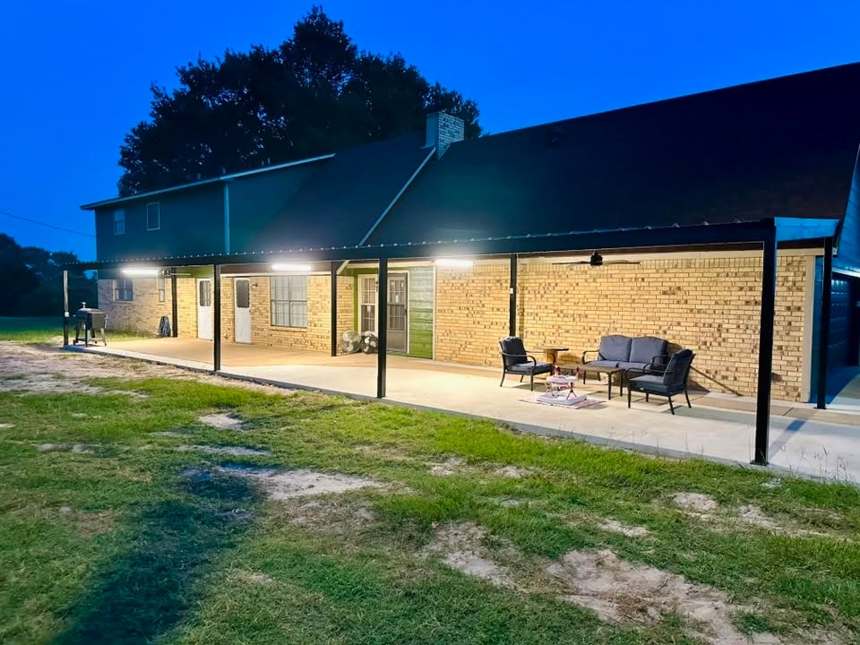 Steel patio cover on brick home lit up at night